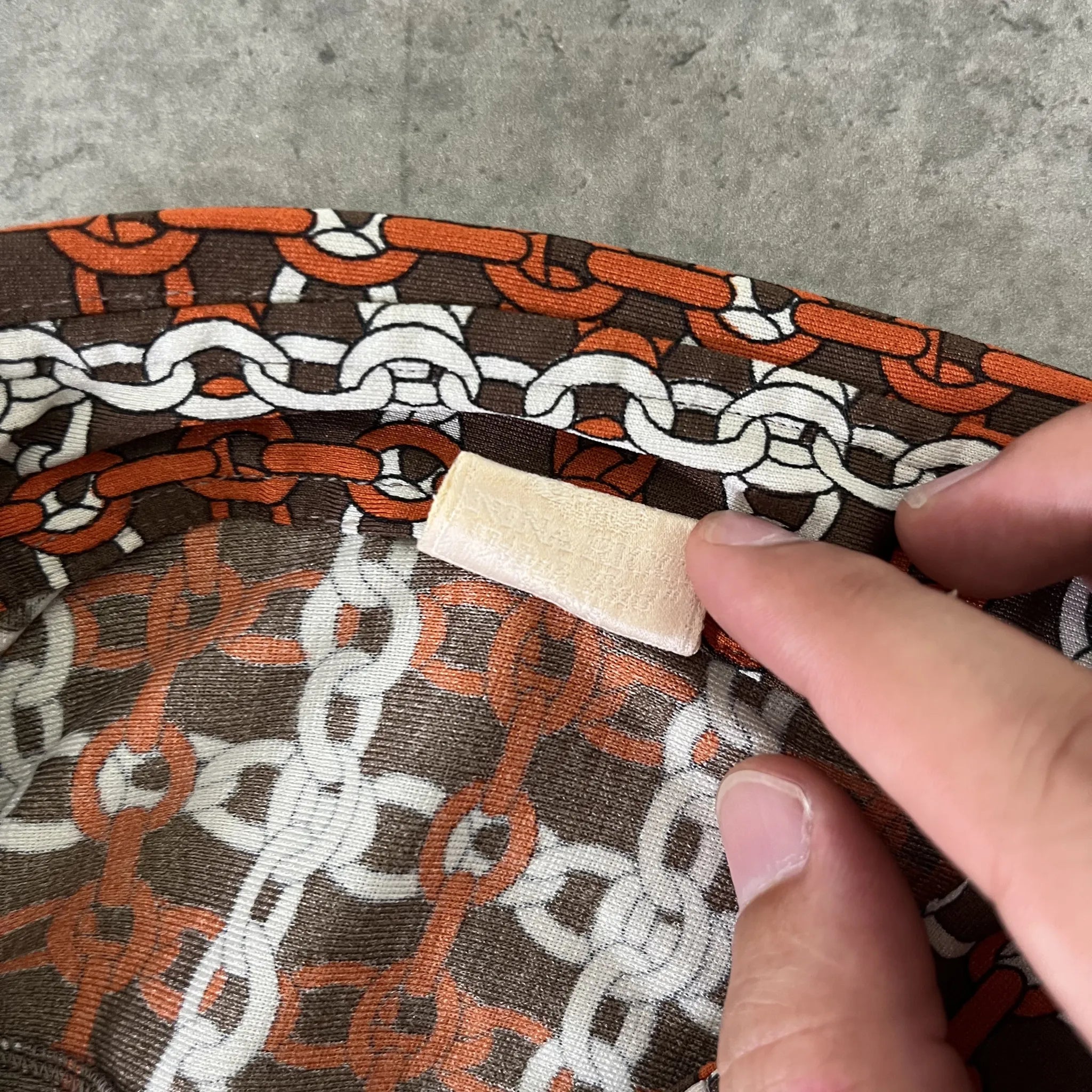 Détail étiquette Nina Ricci au col du chemisier femme marron à motifs, taille 36